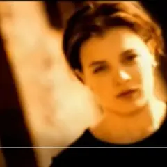 Kobieta w czarnej bluzce, w tle pasy światła i cienia. "More" i "Magazyn" na dole. Freed from desire tłumaczenie.