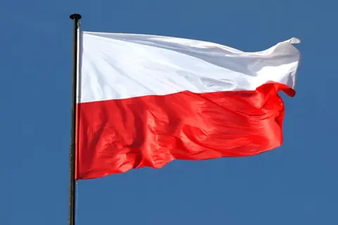 Biało-czerwona flaga Polski powiewa na wietrze. To symbol wolności, jak w piosence "Co to jest niepodległość tekst".