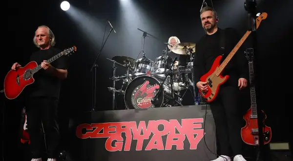 Czerwone gitary na scenie, jak jesienny deszcz dźwięków. Zespół gra, a na tle logo zespołu.