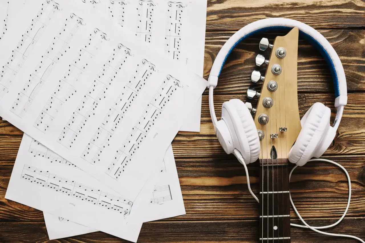 Nuty na fortepian i gitarę, słuchawki. Może to tekst piosenki